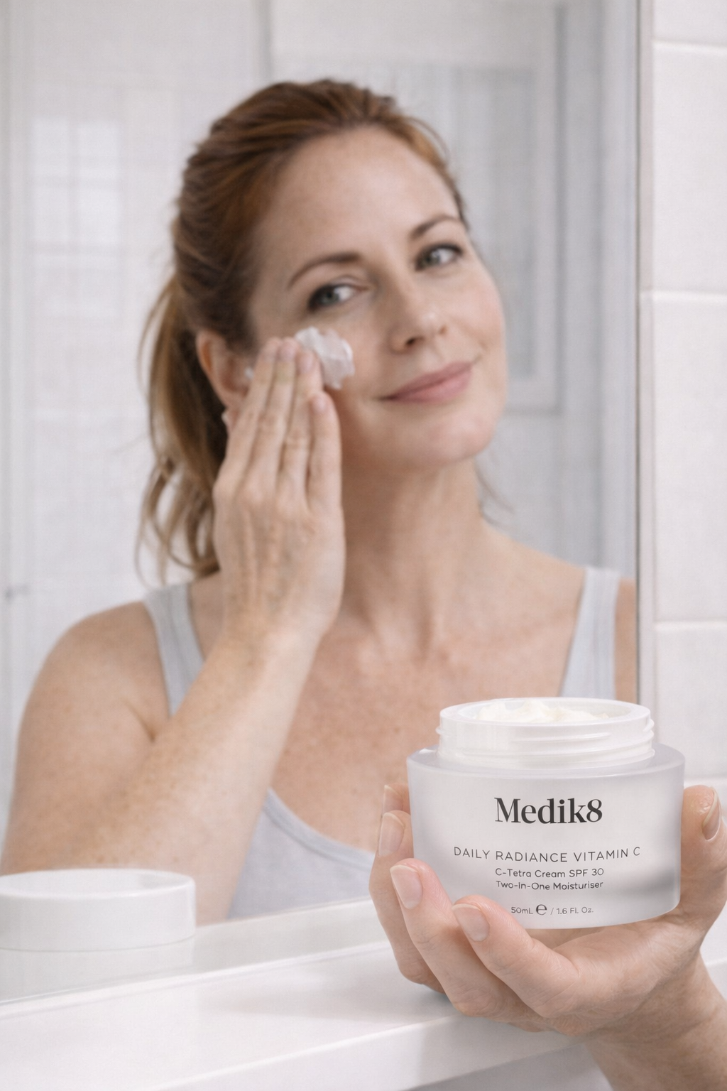 Donna sorridente che applica crema viso Medik8